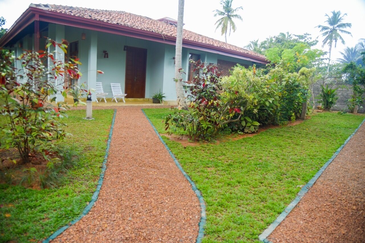 A house with a tiled roof, a covered porch, and a gravel pathway leading to the entrance.