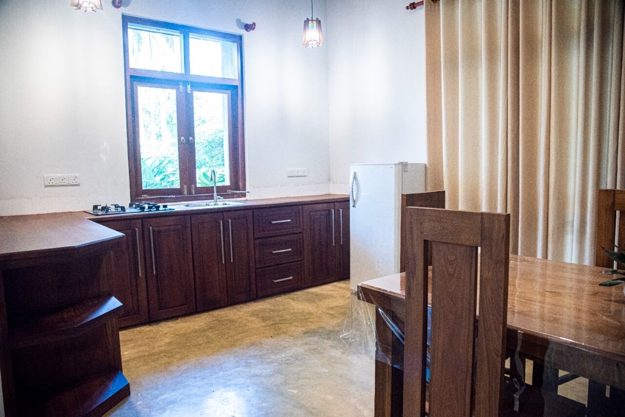 Une cuisine avec des meubles de rangement en bois, une fenêtre et un réfrigérateur.