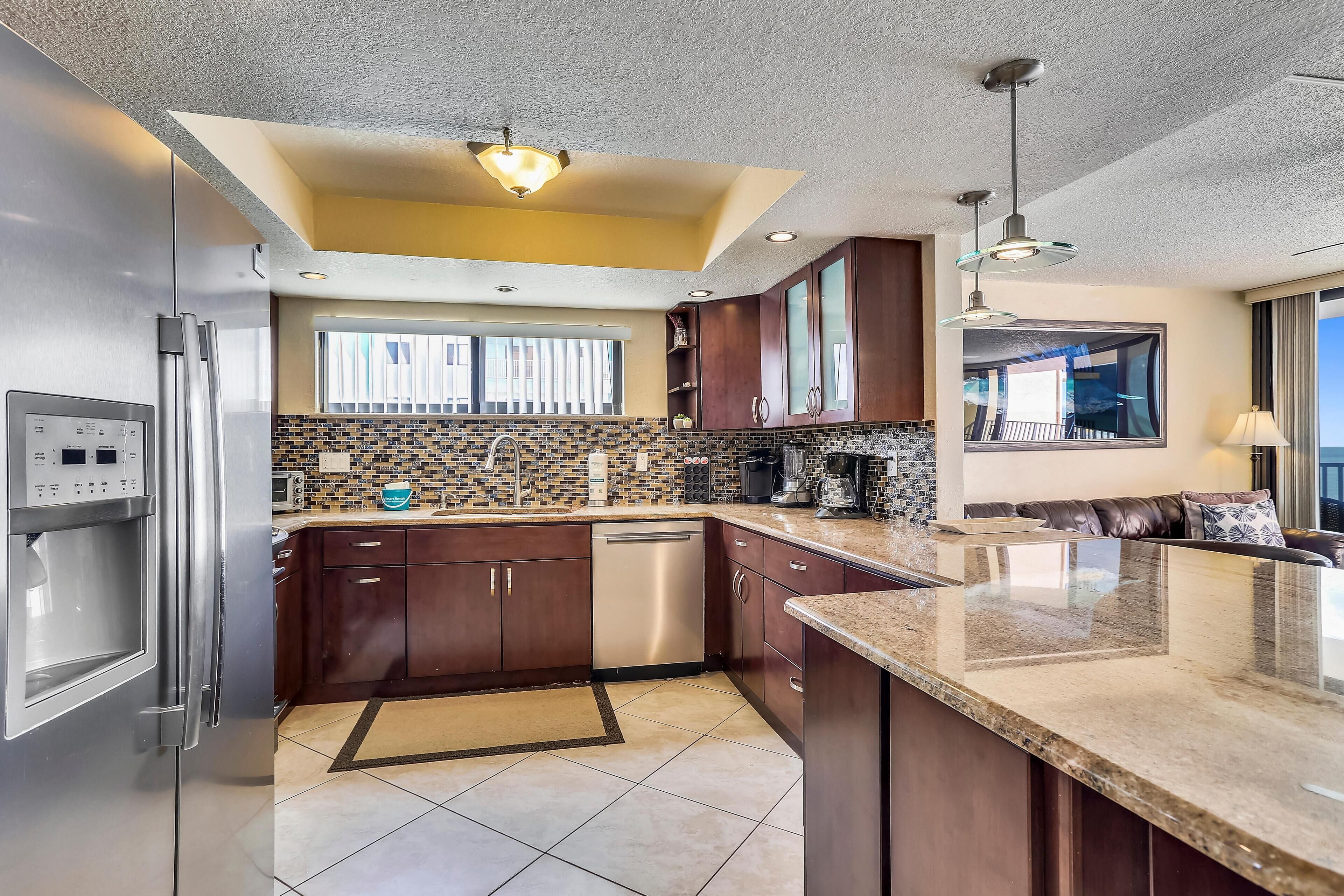 A modern kitchen with dark wood cabinets, stainless steel appliances, and a large island with a granite countertop.