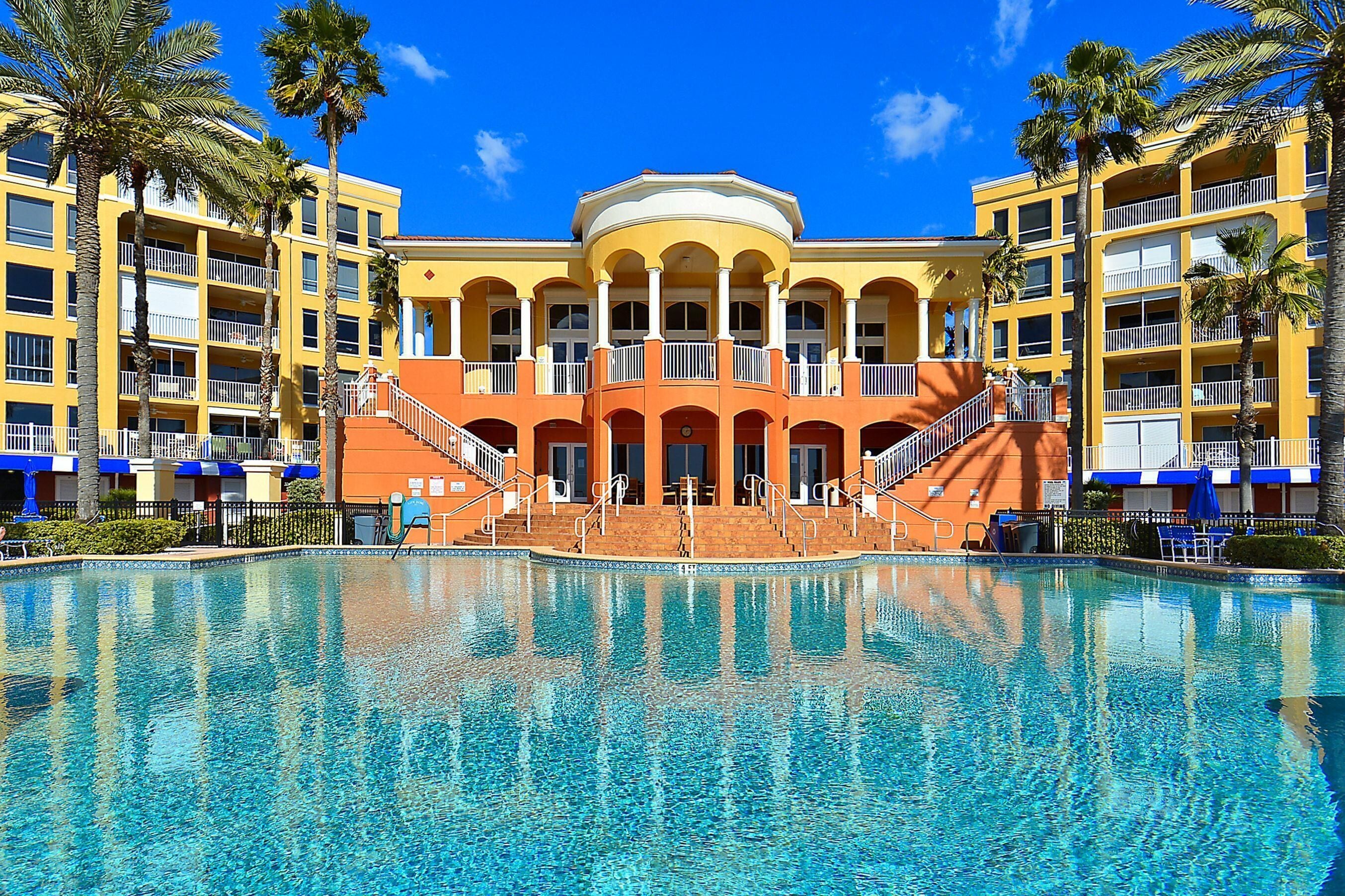 Un hôtel doté d’une grande piscine, de nombreux balcons et de palmiers.