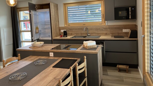 A compact kitchen with a wooden island, a built-in microwave, and a window with blinds.