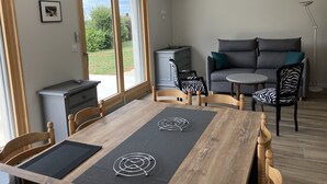 A modern living room with a wooden dining table, a grey sofa, and a zebra-patterned chair.