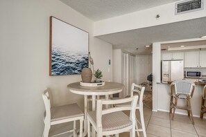Enjoy meals in this cozy dining area with a round table and four chairs, featuring a beautiful seascape above.