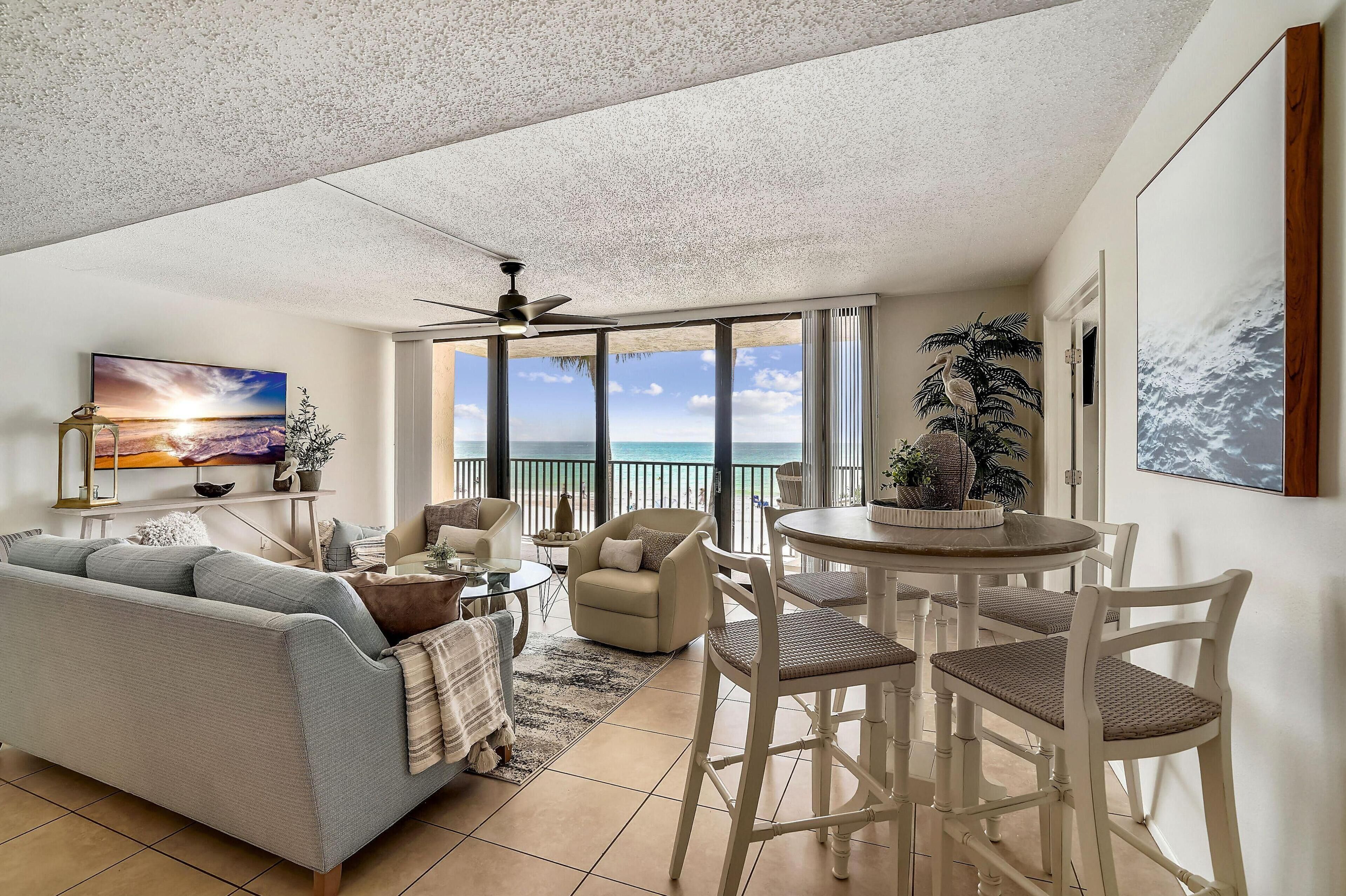 A spacious living area with a balcony, a sofa, a dining table, and chairs.