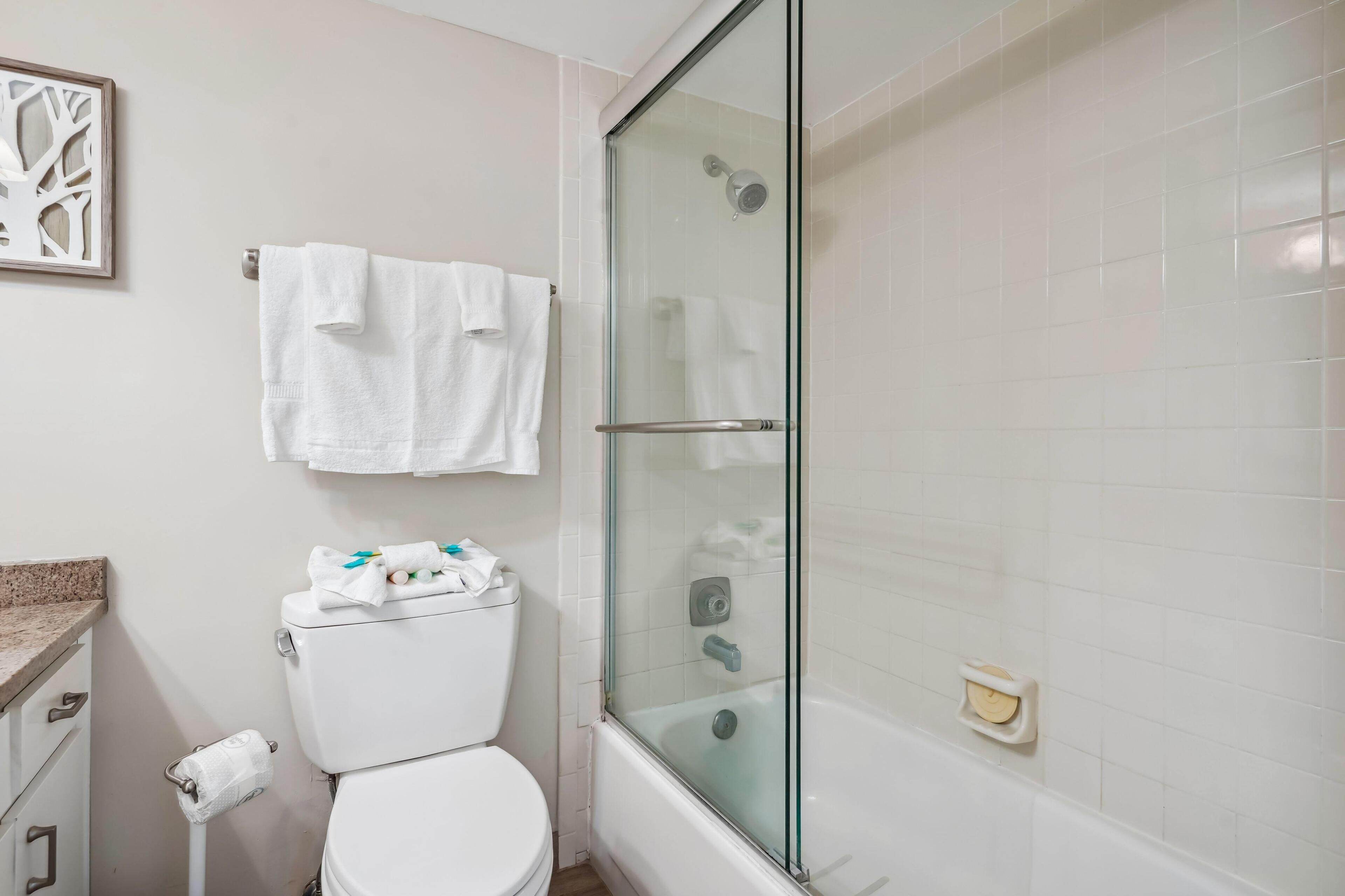Un baño con inodoro, cabina de ducha de vidrio y lavabo.