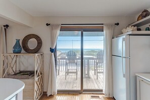 Una cocina con vistas al mar, un comedor con asientos exteriores y un refrigerador.