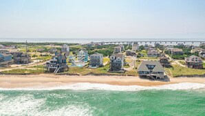 Un quartier résidentiel en bord de mer, avec des maisons situées près de la plage et une jetée en arrière-plan.