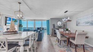 A spacious dining area with a large table and chairs, a ceiling fan, and a view to the outside.