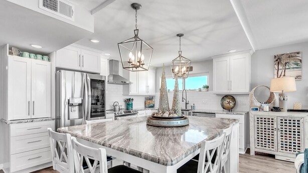 A modern kitchen with white cabinetry, a large marble island, and pendant lighting.