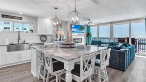A spacious kitchen with a central island, white cabinetry, and a large window overlooking the beach.