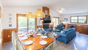 Ein geräumiger Wohnbereich mit einem Holzes Esstisch, der für eine Mahlzeit gedeckt ist, einem blauen Sofa und einem Fernseher.