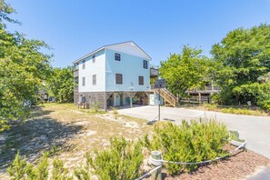 A two-story building with a flat roof, a front porch, and a staircase leading to a second level. - Pet-friendly oceanside home in Duck with hot tub! (Duck)