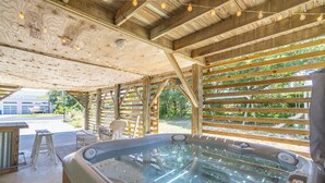 Ein Whirlpool unter einer Holzkonstruktion mit Blick auf grüne Landschaft.