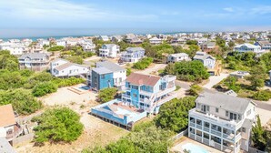Un quartier résidentiel situé sur la côte, composé de nombreuses maisons à deux étages, dont certaines sont dotées de balcons, et offrant une vue dégagée sur l’océan.