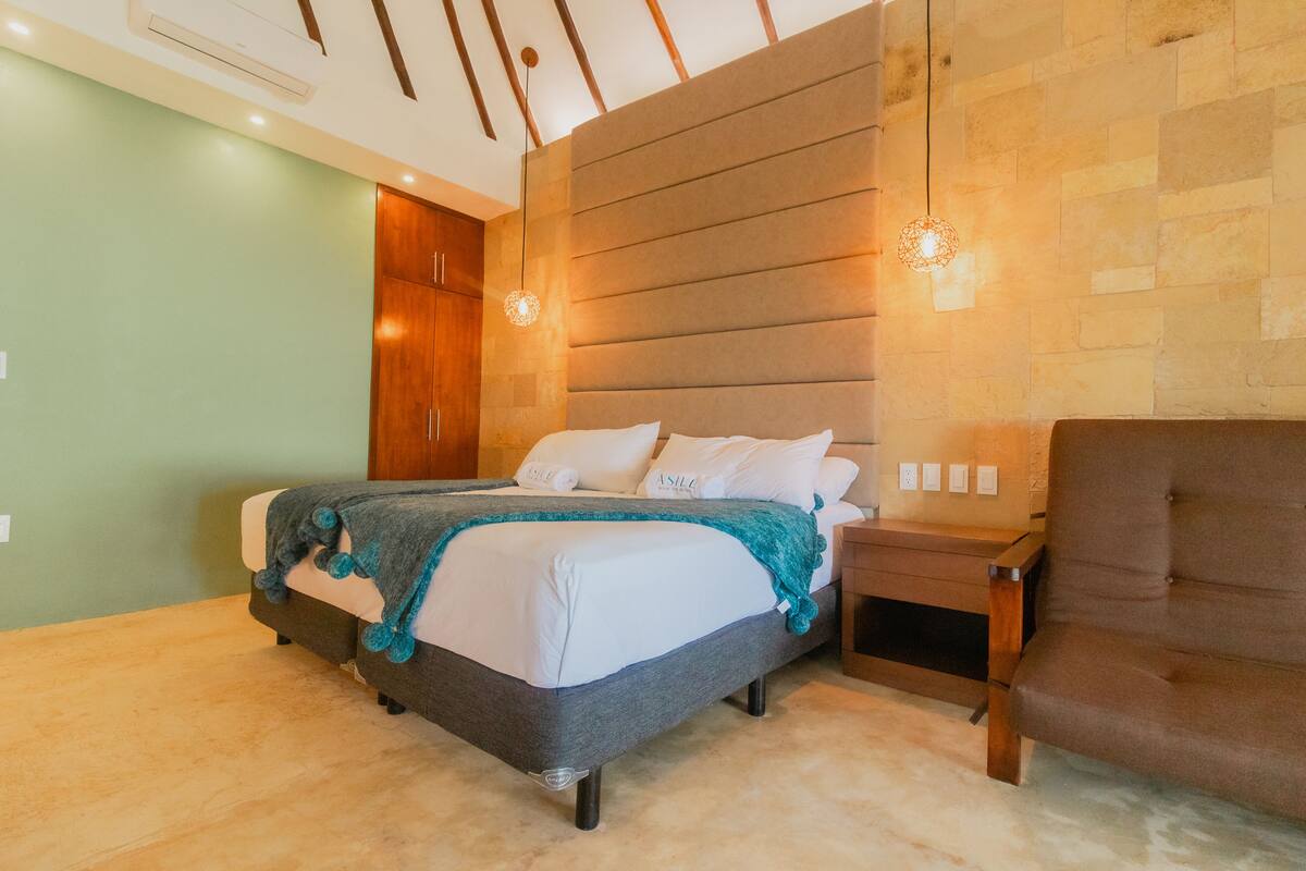 Un dormitorio moderno con una cama grande, un armario de madera y un sillón marrón.