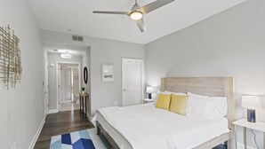 A bedroom with a bed, a ceiling fan, a nightstand, a lamp, and a geometric-patterned rug. - Chic 2BR Apt, Steps from N Main St, Balcony View
 (Greenville)