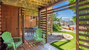 Een houten terras met twee groene stoelen, een tafel en een pergola.