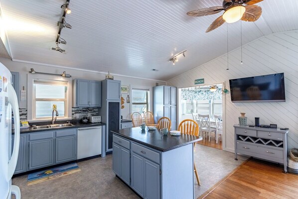A modern kitchen with grey cabinets, a central island, and a dining area with wooden chairs.