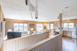 Un vaste espace de vie doté d’un haut plafond, d’une table à manger et d’un coin cuisine.