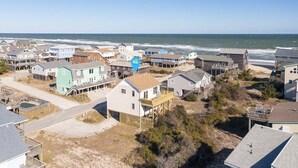 A coastal residential area with houses, some with wooden decks and balconies, and a view of the ocean.