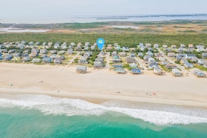 Vista aérea de una zona residencial costera con casas, una playa y una masa de agua.