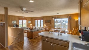 A spacious living area with a wooden floor, a sofa, a dining table, and a kitchen area with a large island.