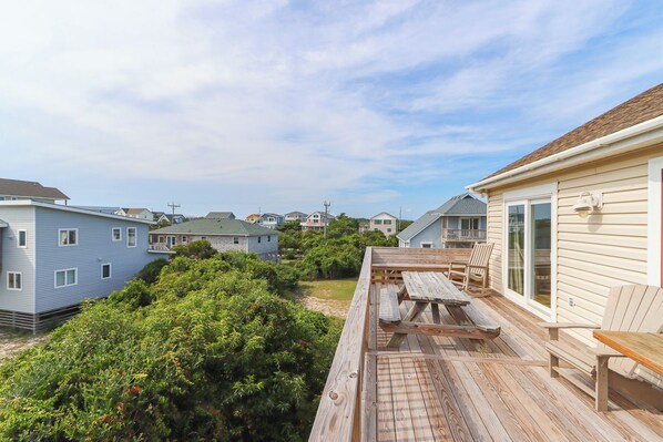 Une terrasse en bois, agrémentée de mobilier d’extérieur, entourée de maisons aux toits de différentes couleurs.