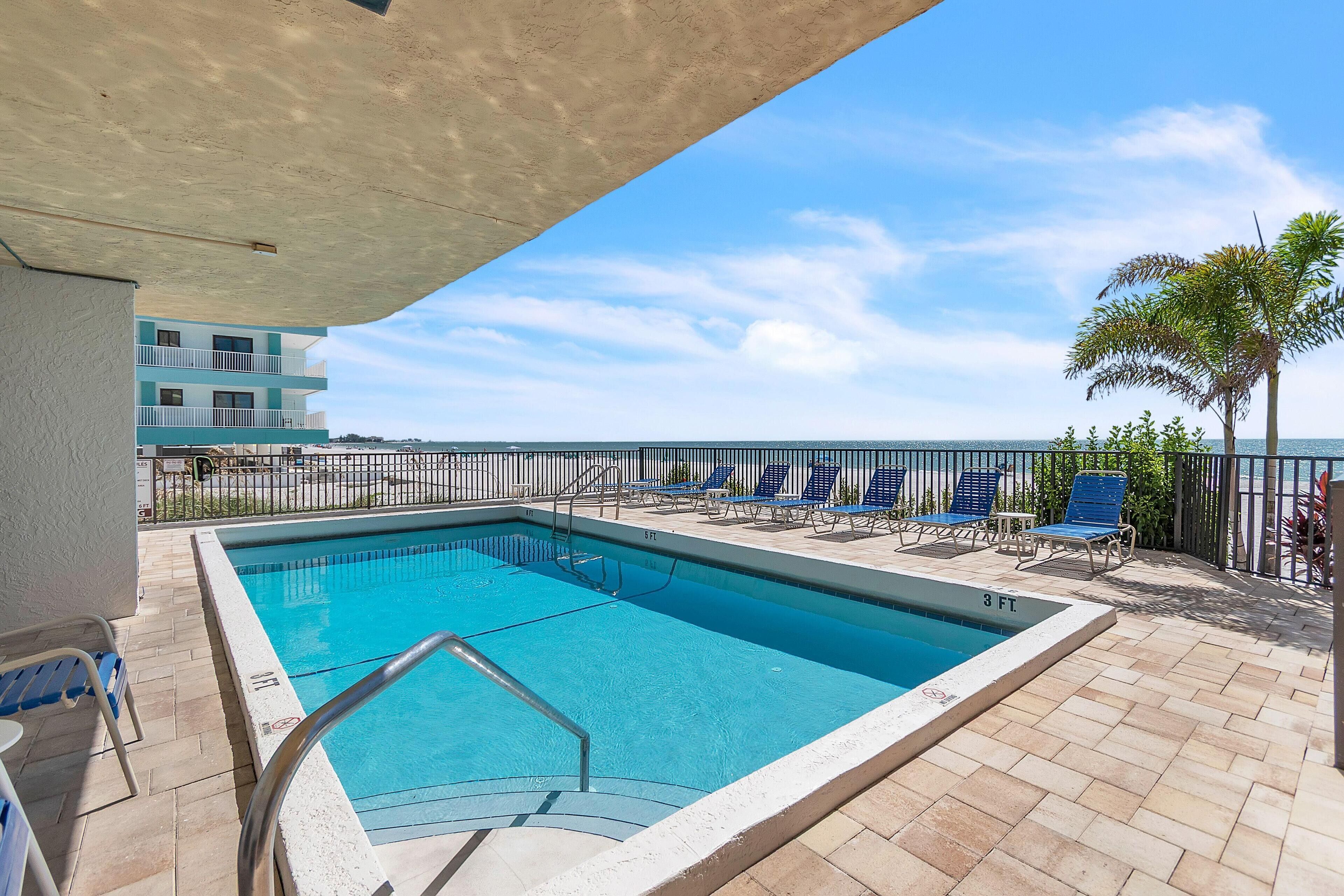 A swimming pool with a 3 ft depth, surrounded by blue lounge chairs and a tiled deck.
