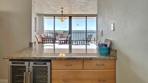 Una cocina con encimeras de granito, armarios de madera y vistas a un balcón con mobiliario exterior.