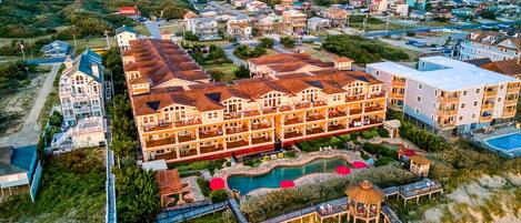 A resort with multiple buildings, a swimming pool, and a beach area.
