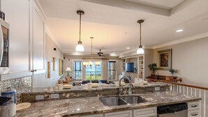 A spacious kitchen with granite countertops, a double sink, and a dishwasher. - Luxury oceanfront condo with community indoor & outdoor pools, hot tub & more (Kill Devil Hills)