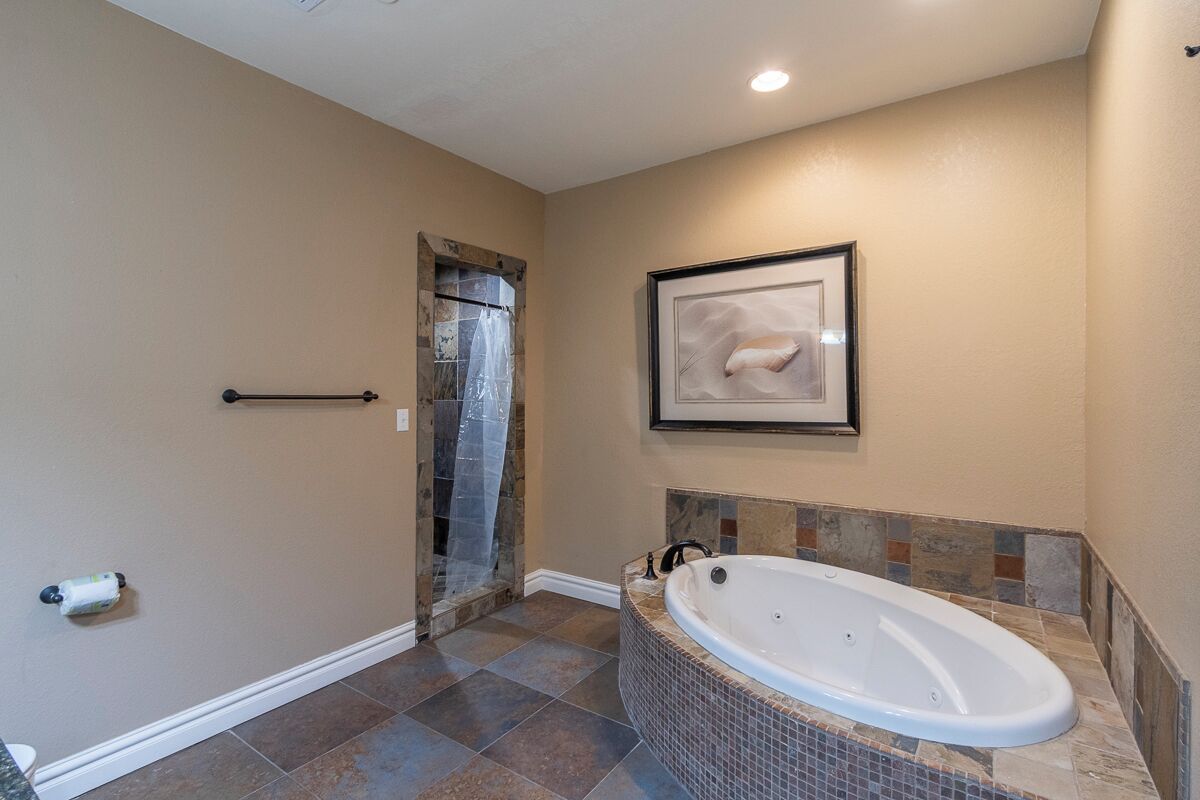 A bathroom with a bathtub, tiled floor, and a framed picture on the wall.