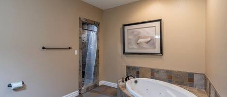 A bathroom with a bathtub, tiled floor, and a framed picture on the wall.