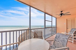 A balcony with a view of the beach, a ceiling fan, and a table and chairs. - Villa Madeira 202 (Madeira Beach)