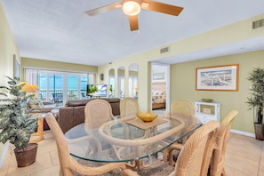A dining area with a glass table, wicker chairs, and a ceiling fan. - Villa Madeira 202 (Madeira Beach)