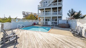 A multi-story building with a pool, deck chairs, and a fenced area. - Spacious pet-friendly home on Hatteras Island w/ a private pool & hot tub! (Avon)