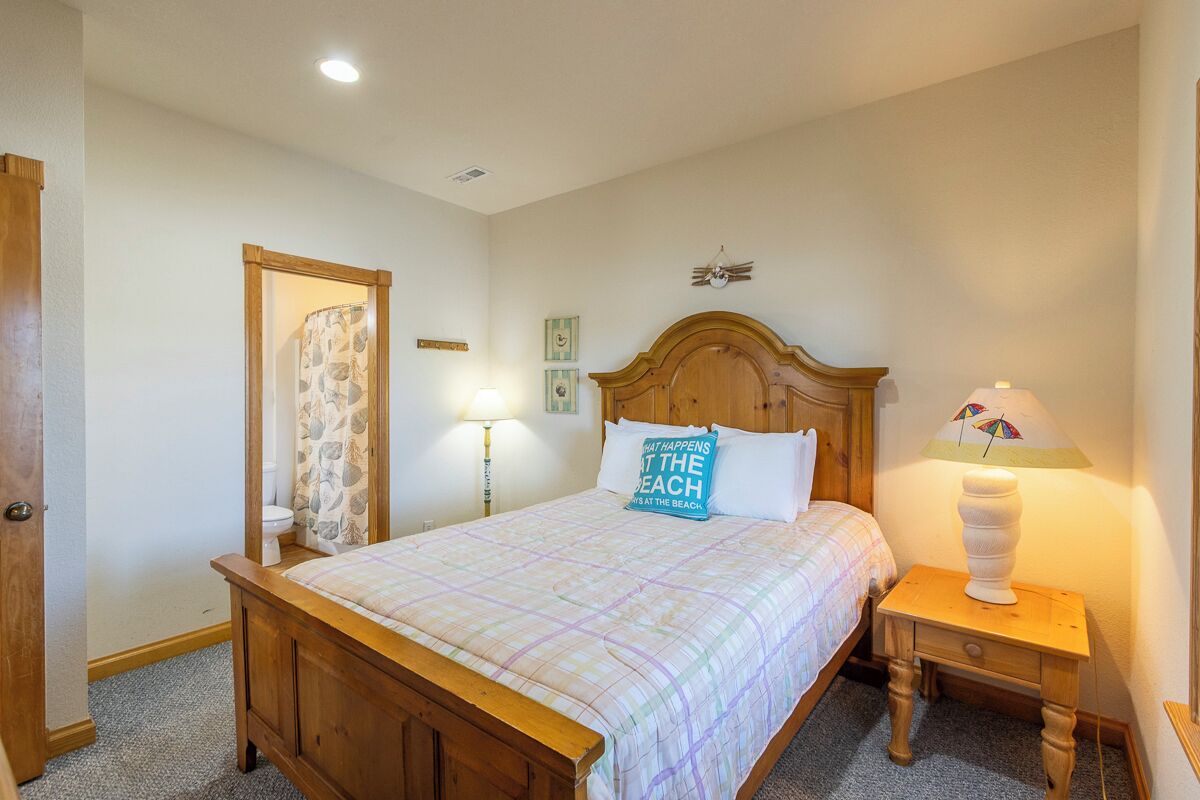 Une chambre à coucher avec un lit en bois, une table de chevet avec une lampe, une porte et une étagère fixée au mur.