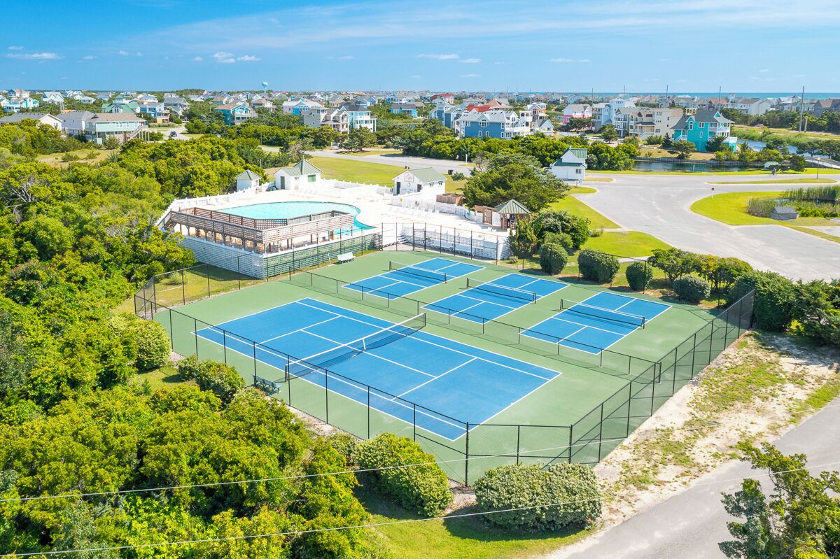 Een tennisbaan omringd door weelderig groen en woongebouwen.