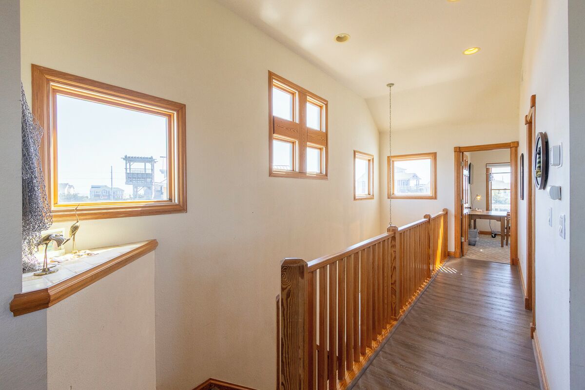A hallway with wooden railings, multiple windows, and a view of a building outside.