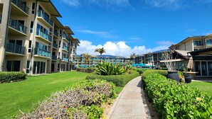 A hotel courtyard with a central pathway, lush green landscaping, and multi-story buildings with balconies.