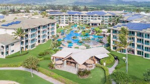 A resort with multiple buildings, a central pool area with water features, and surrounding greenery.