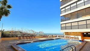 A swimming pool with lounge chairs and a view of the ocean.