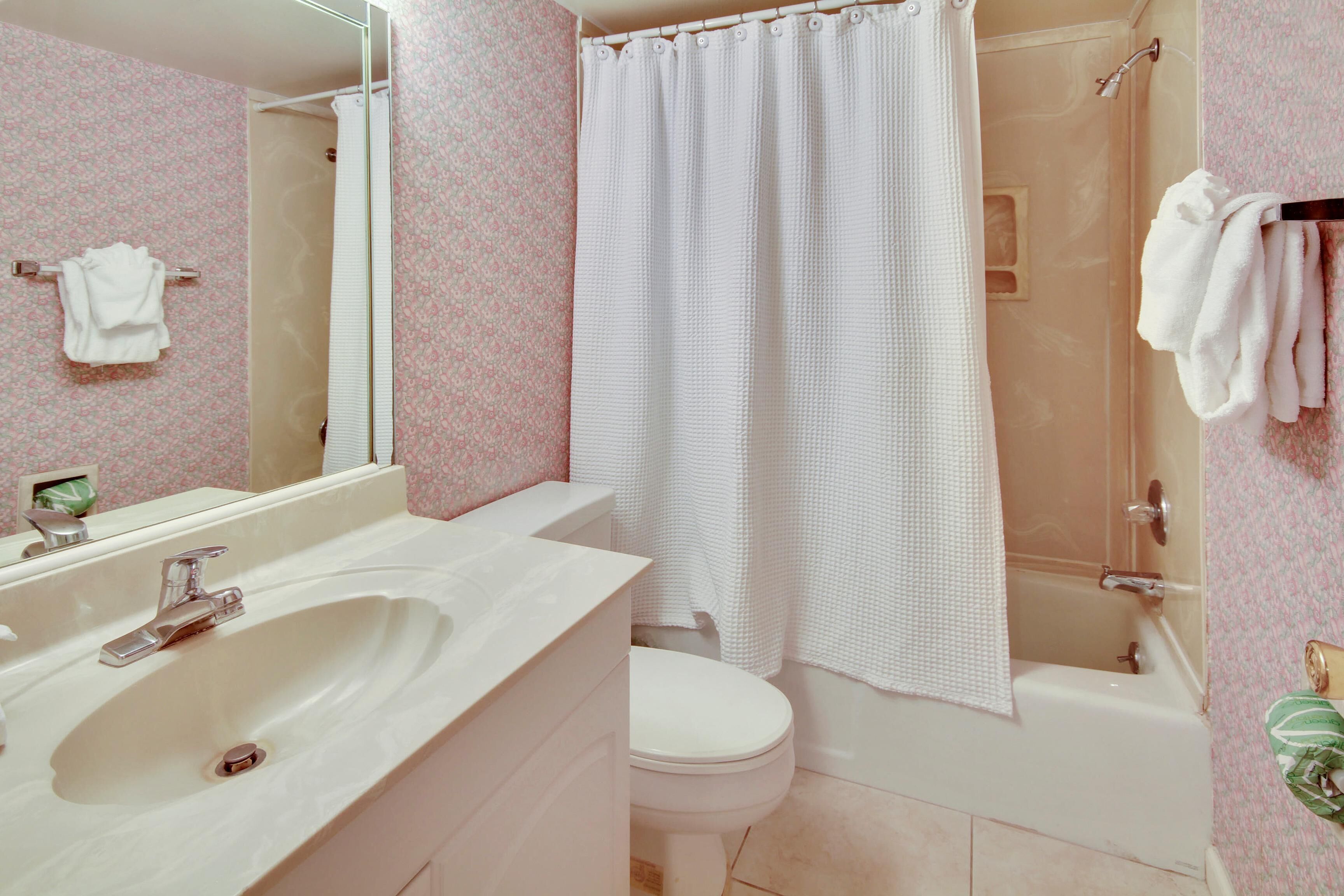A bathroom with a sink, toilet, and shower area.
