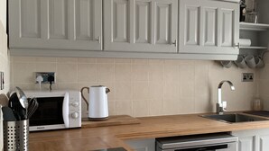 Una cocina moderna con armarios blancos, microondas, cafetera y lavavajillas.