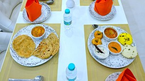Una mesa de comedor dispuesta con varios platos de comida, botellas de agua y servilletas anaranjadas.