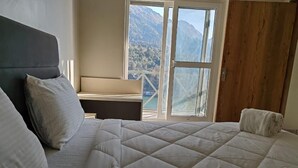 Un dormitorio con cama, mesita de noche y ventana con vistas a la montaña.