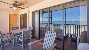 Ein Balkon mit Tisch und Stühlen, einem Deckenventilator und Blick auf den Strand.