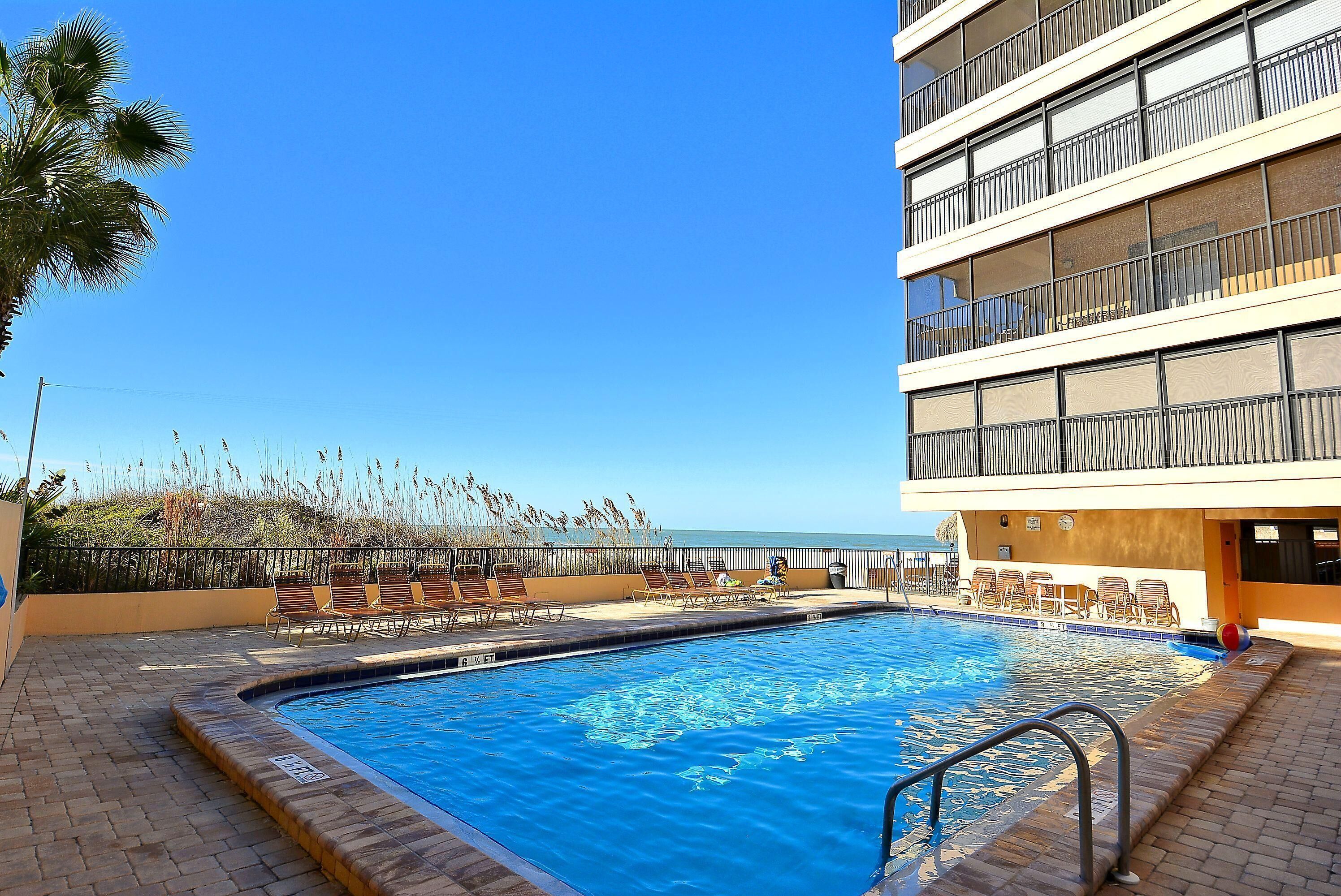 A swimming pool with lounge chairs and a view of the ocean.