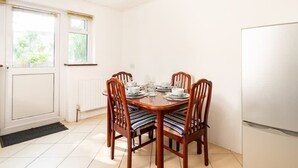 Ein Essbereich mit einem Holztisch, gedeckt für vier Personen, umgeben von Stühlen mit gestreiften Kissen.
