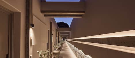 A corridor with potted plants, a stone wall, and a wooden beam ceiling.